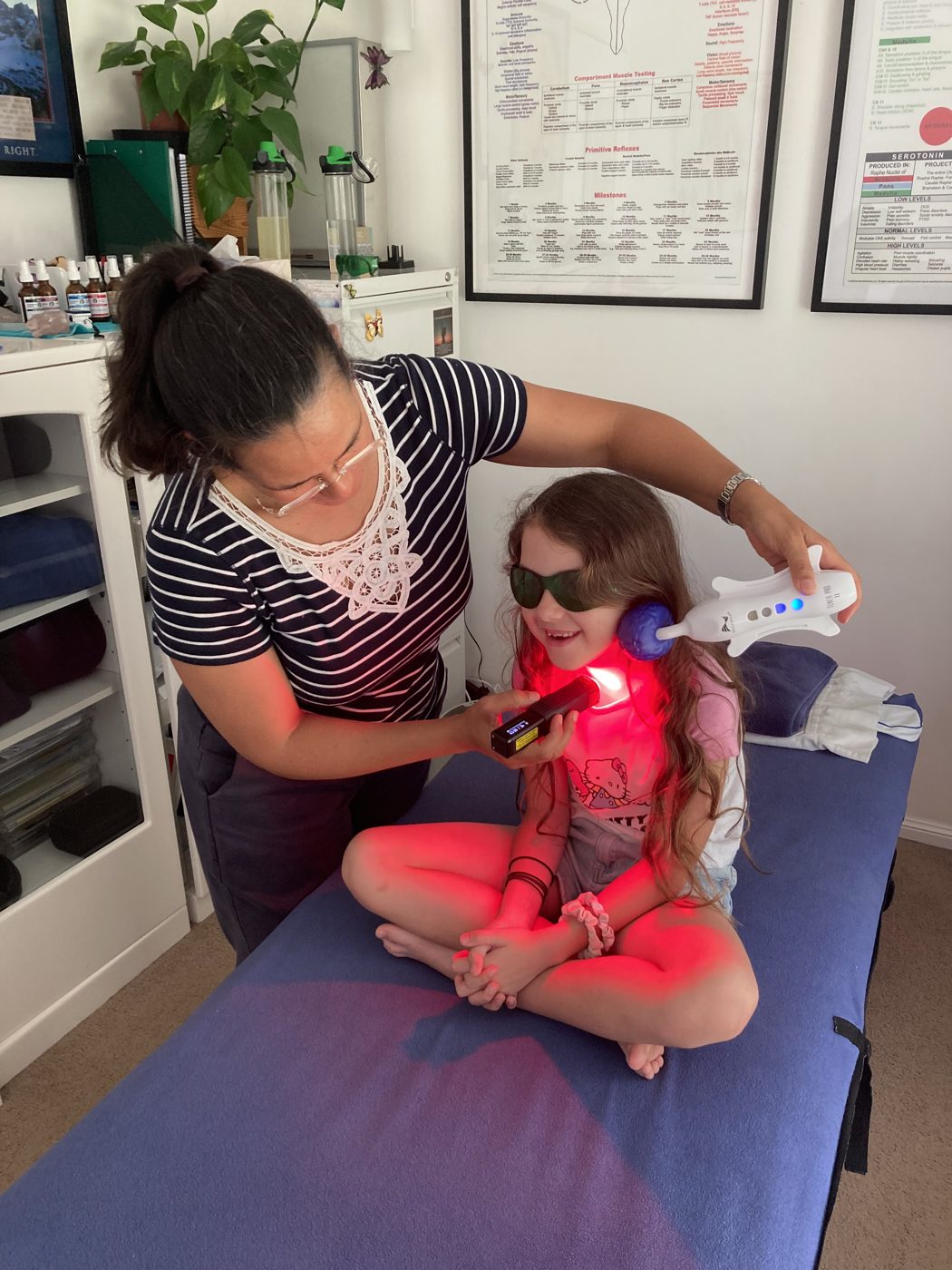 A practitioner using red light and Rezzimax therapy with a young girl in clinic